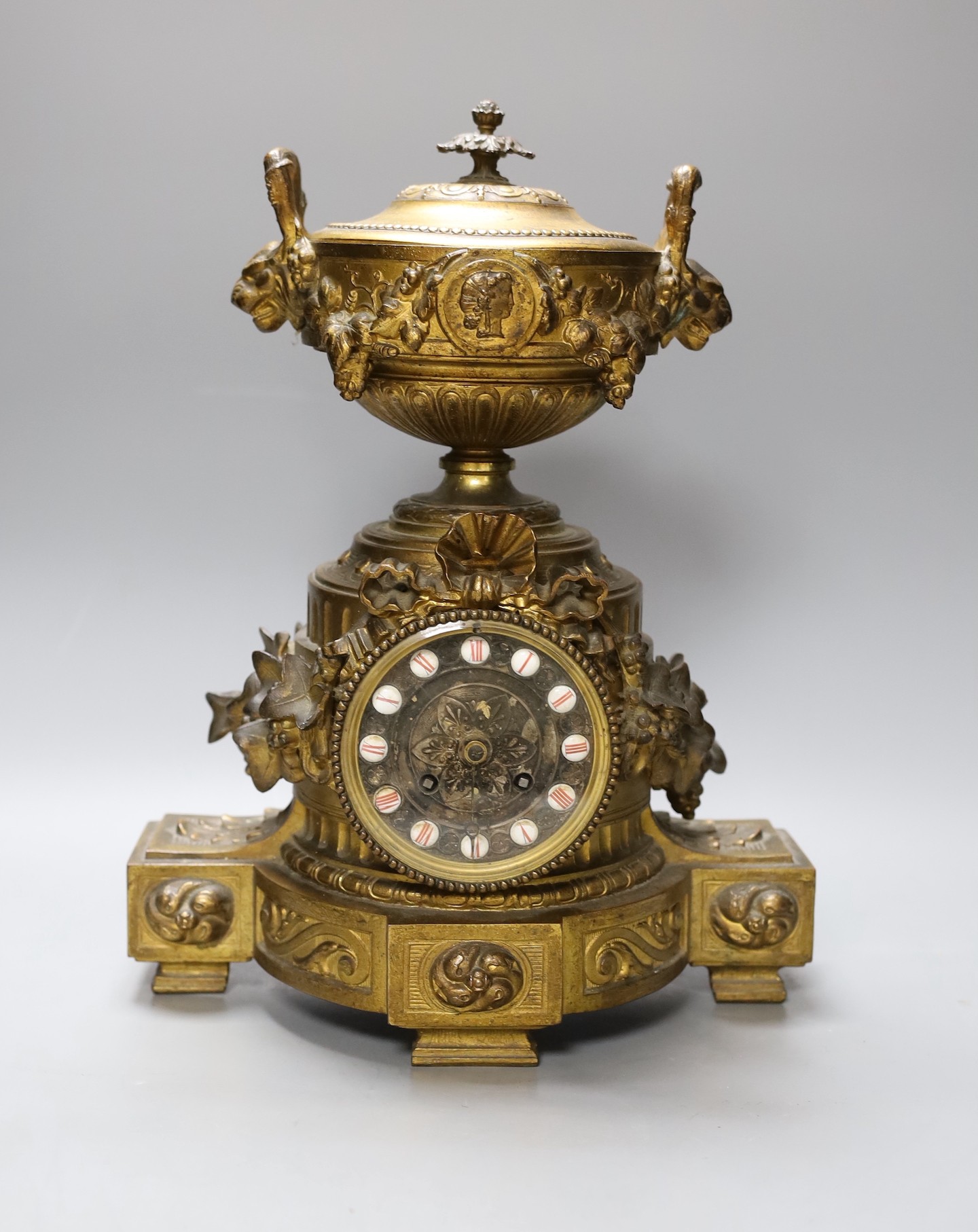 A French gilt metal mantel clock, designed with ornate vines and an urn, 38 cms high